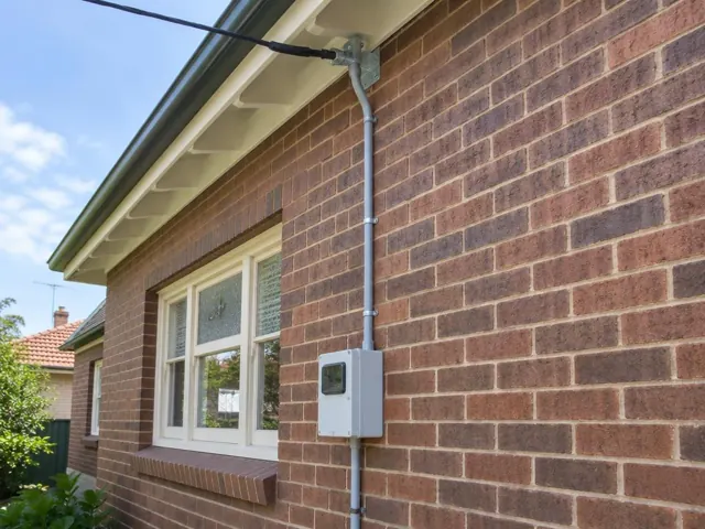 Overhead service cable and new point-of-attachment bracket on a brick house exterior in Willoughby